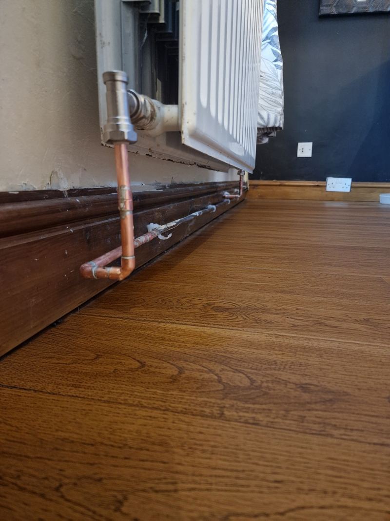 Finished radiator with new valve and neat copper pipe into a wooden floor